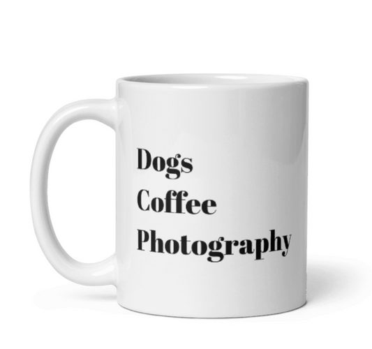 A white mug with text Dogs, Coffee, Photography stacked horizontal in black.