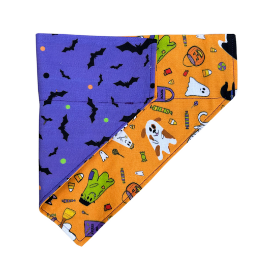 Halloween-themed fabric with purple side featuring black bats and orange side with ghosts, pumpkins, and candy.