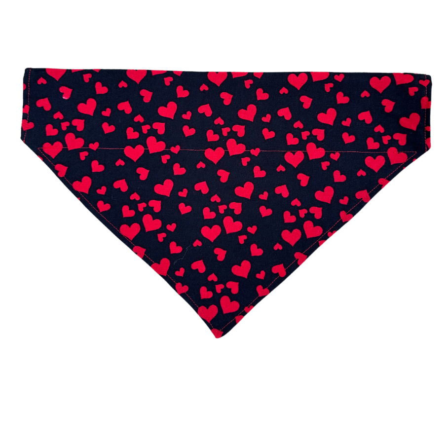 A reversible dog bandana with one side featuring a black fabric with red hearts.