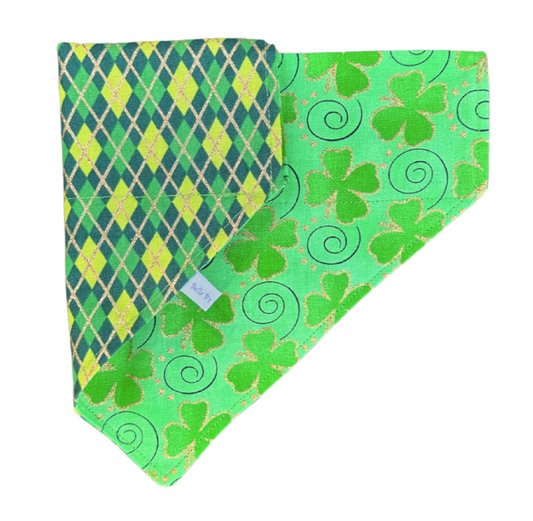 A reversible dog bandana with one side featuring a green shamrock pattern and the other side showcasing a green and gold argyle pattern.